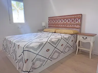 a bedroom with a bed and a table and a window at Luz de Conil is a modern villa next to Playa Fontanilla in Conil de la Frontera