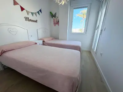 two beds in a small room with a window at Luz de Conil is a modern villa next to Playa Fontanilla in Conil de la Frontera