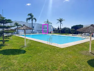 a swimming pool with umbrellas in the grass at Luz de Conil is a modern villa next to Playa Fontanilla in Conil de la Frontera