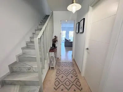 a hallway with a staircase with a white stair case at Luz de Conil is a modern villa next to Playa Fontanilla in Conil de la Frontera