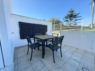 a table and chairs sitting on a patio at Luz de Conil is a modern villa next to Playa Fontanilla in Conil de la Frontera