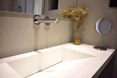 a white sink with a mirror and a vase of flowers at Apartamento Los Olivos Jerez in Jerez de la Frontera