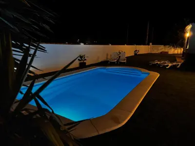 a blue swimming pool in a yard at night at Azul Sancti Petri in Chiclana de la Frontera