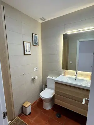 a bathroom with a toilet and a sink and a mirror at Apartmento en La Barrosa con piscina in Novo Sancti Petri
