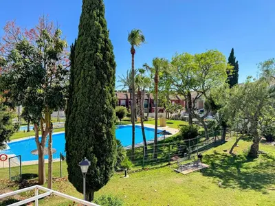 a resort with a swimming pool and a palm tree at Apartmento en La Barrosa con piscina in Novo Sancti Petri