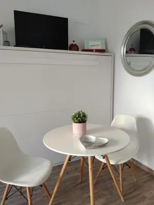 a white table and chairs in a room with a tv at Apartamento Dali in El Puerto de Santa María