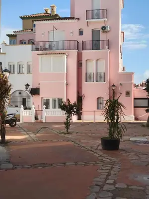 a pink building with plants in front of it at Apartamento Dali in El Puerto de Santa María