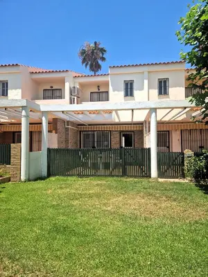 a house with a fence and a palm tree in the background at Primera Línea de Playa Casa adosada La Balconera in Chiclana de la Frontera