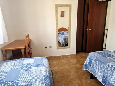 a bedroom with two beds and a table and a mirror at Primera Línea de Playa Casa adosada La Balconera in Chiclana de la Frontera