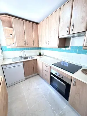 a kitchen with wooden cabinets and a sink and a dishwasher at Apartamento Empul Rota Príncipe in Rota