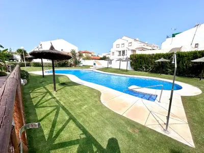 a swimming pool with an umbrella in a yard at Apartamento Empul Rota Príncipe in Rota