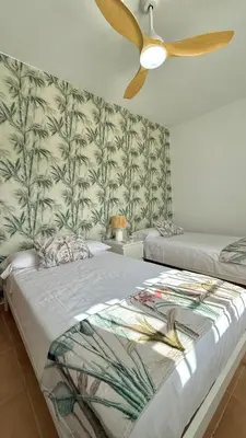a bedroom with two beds and a ceiling fan at Mirador las Cumbres Conil - Piscina Jardín XL in Conil de la Frontera