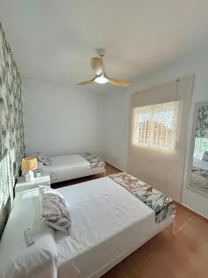 a bedroom with two beds and a ceiling fan at Mirador las Cumbres Conil - Piscina Jardín XL in Conil de la Frontera