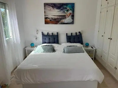 a bedroom with a white bed with a painting above it at Villa Costa Ballena in Rota