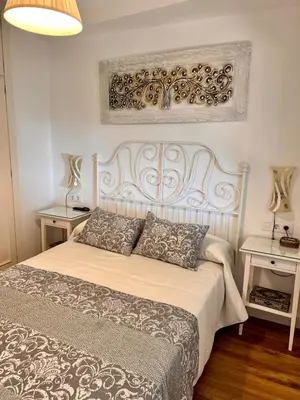 a bedroom with a large white bed with two tables at Apartamento en Fuentebravia in El Puerto de Santa María