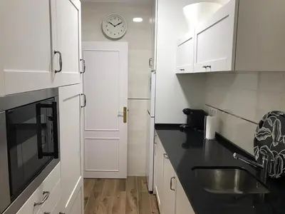 a kitchen with white cabinets and a clock on the wall at Apartamento en Fuentebravia in El Puerto de Santa María