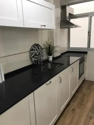 a kitchen with white cabinets and black counter tops at Apartamento en Fuentebravia in El Puerto de Santa María