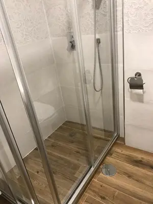 a shower with a glass door on a wooden floor at Apartamento en Fuentebravia in El Puerto de Santa María