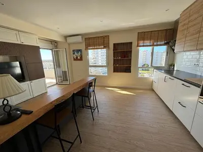 a kitchen with white cabinets and a table with chairs at Apartamento Valdelagrana vistas al Mar in El Puerto de Santa María