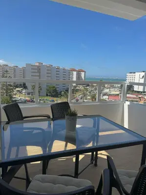 a glass table on a balcony with a view of a city at Apartamento Valdelagrana vistas al Mar in El Puerto de Santa María