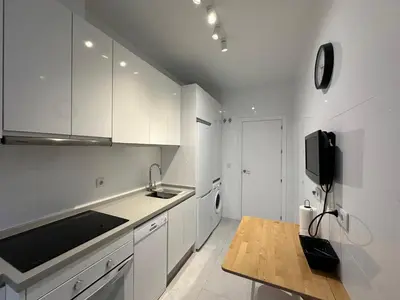 a kitchen with white cabinets and a tv on the wall at La Caleta in Cádiz