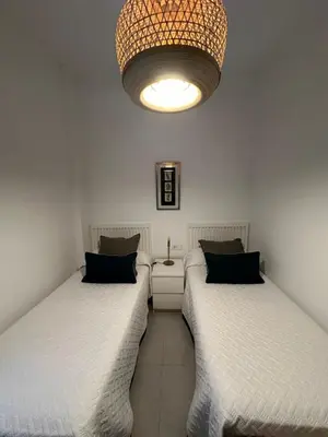 two twin beds in a room with a chandelier at La Caleta in Cádiz