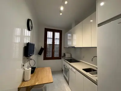 a kitchen with white cabinets and a wooden table at La Caleta in Cádiz