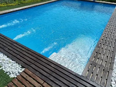 a pool with blue water and a wooden deck at Villa Paquita in Vallejas