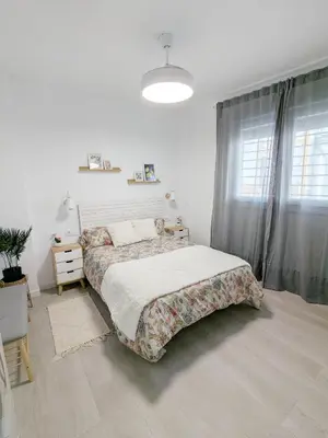 a white bedroom with a bed and a window at Apartamento Victoria in San Fernando