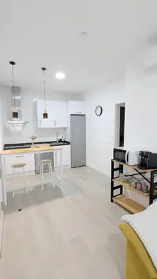 a white kitchen with a table and a refrigerator at Apartamento Victoria in San Fernando