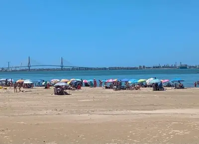 a group of people sitting on a beach with umbrellas at 4 dormitorios Valdelagrana in El Puerto de Santa María