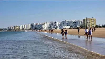 a group of people walking on the beach at 4 dormitorios Valdelagrana in El Puerto de Santa María