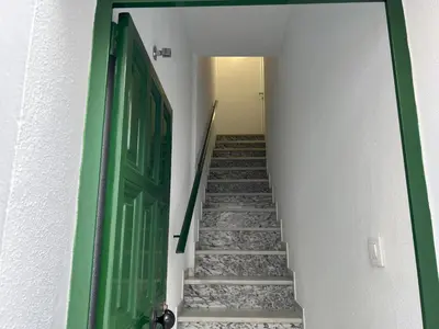 a hallway with a green door and stairs at Casa Álamo en Chipiona in Chipiona
