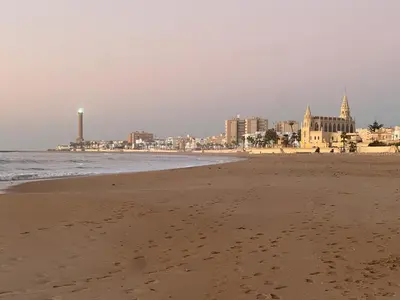 a sandy beach with a city in the background at Casa Álamo en Chipiona in Chipiona