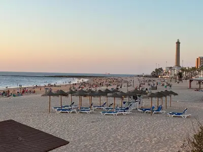 a beach with chairs and umbrellas and a crowd of people at Casa Álamo en Chipiona in Chipiona