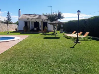 a house with a yard with chairs and an umbrella at Casa Juan José in Conil de la Frontera