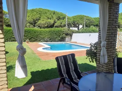 a patio with a table and chairs and a swimming pool at Casa Juan José in Conil de la Frontera
