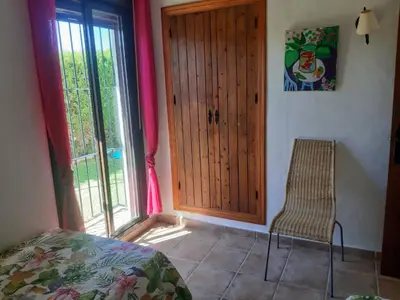a bedroom with a door and a chair and a window at Casa Juan José in Conil de la Frontera
