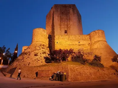 a person walking in front of a large castle at Alojamiento Montero in Sanlúcar de Barrameda