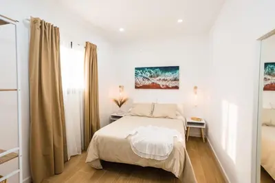 a white bedroom with a bed and a window at La casita nueva in Cádiz
