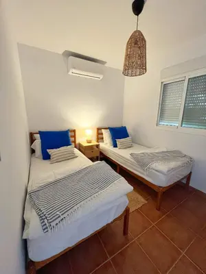 two beds in a room with blue pillows at Chalet Vacacional ELIÁ -Piscina Privada, BBQ, Wifi in Chiclana de la Frontera
