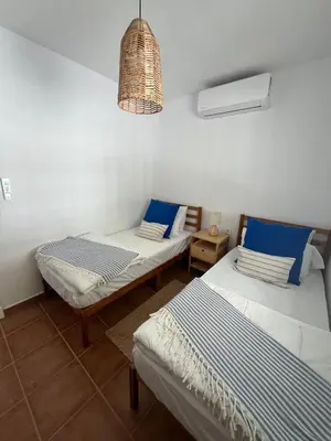 a room with two beds and a hanging light at Chalet Vacacional ELIÁ -Piscina Privada, BBQ, Wifi in Chiclana de la Frontera