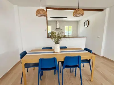 a dining room with a wooden table and blue chairs at Chalet Vacacional ELIÁ -Piscina Privada, BBQ, Wifi in Chiclana de la Frontera