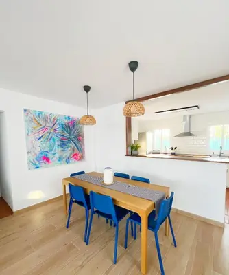 a dining room with a table and blue chairs at Chalet Vacacional ELIÁ -Piscina Privada, BBQ, Wifi in Chiclana de la Frontera