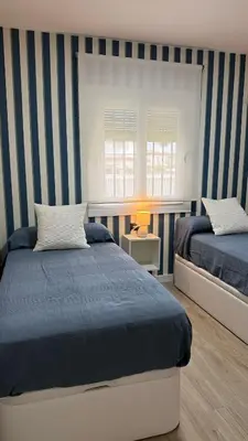 a bedroom with two beds with blue and white stripes at Punto Mágico, apartamento junto al mar in Poblado de Sancti Petri