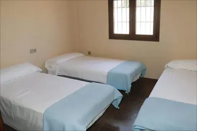 a room with three beds and a window at Villa Dana in Chiclana de la Frontera