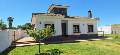 a small white house with a tree in a yard at Villa Dana in Chiclana de la Frontera