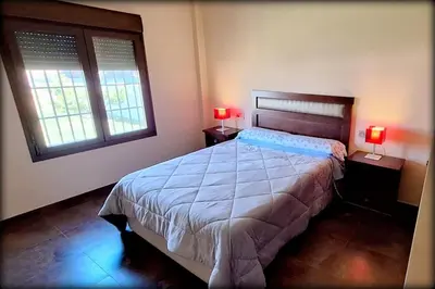 a bedroom with a large bed and two windows at Villa Dana in Chiclana de la Frontera