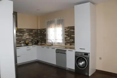 a kitchen with white cabinets and a washer and dryer at Villa Dana in Chiclana de la Frontera