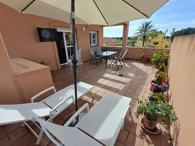 a patio with white tables and chairs and an umbrella at Ático 